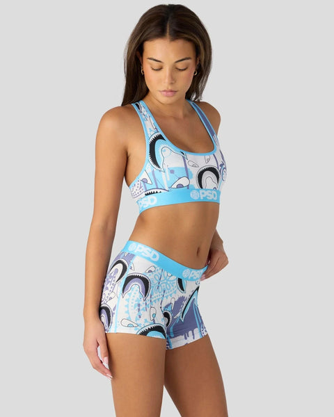 Woman wearing blue and white patterned sports bra and matching shorts with graphic prints and blue waistband.