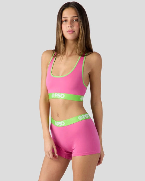 Pink sports bra and shorts set with neon green trim and branding.