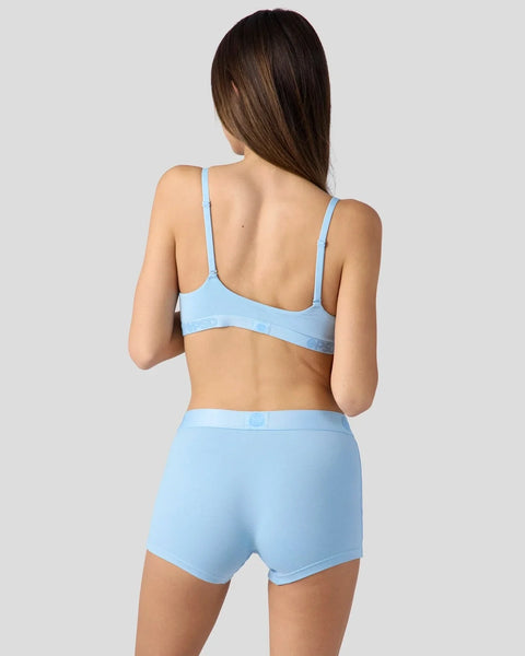 Woman wearing a light blue bralette with thin straps and matching high-waisted shorts, shown from behind.