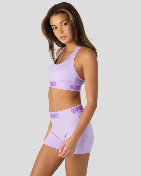 Woman wearing lavender sports bra and shorts set with purple branded waistband.