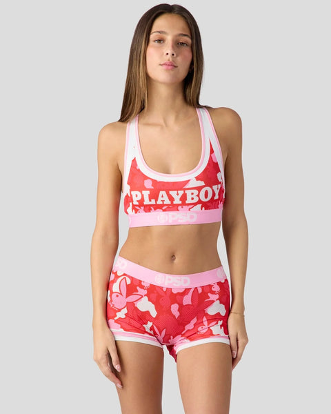 Woman wearing red and white heart-patterned Playboy sports bra and shorts set with pink trim.