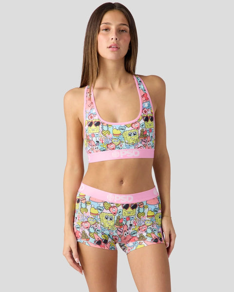 Woman wearing SpongeBob SquarePants printed sports bra and shorts set with pink trim on white background.