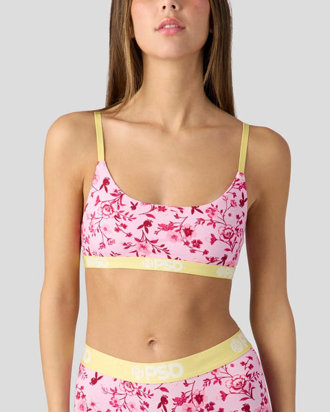 Pink floral bralette with yellow trim and matching low-rise briefs on a model.