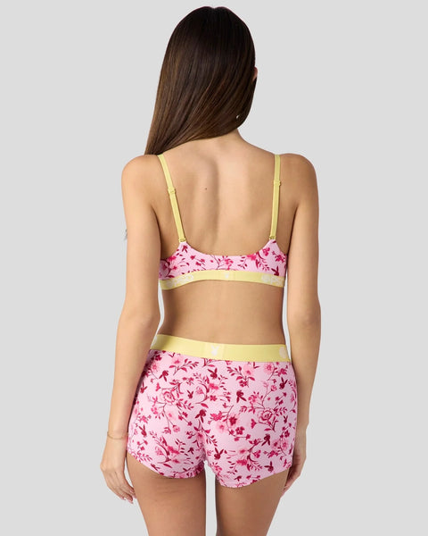 Woman wearing a pink floral print two-piece swimsuit with lime green trim, shown from behind.
