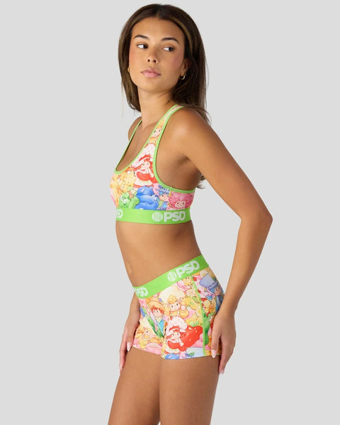 Woman wearing a two-piece set with colorful Strawberry Shortcake and Care Bears characters print and neon green trim with bra