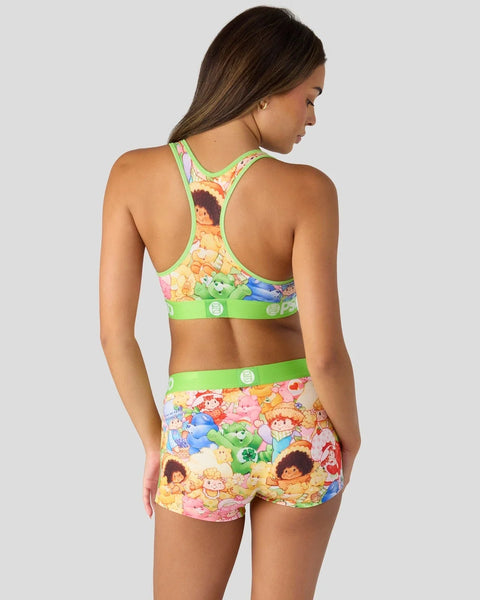 Woman wearing lime green sports bra and matching shorts with colorful Strawberry Shortcake and Care Bears character print.