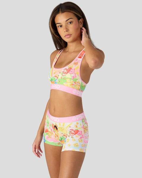 Woman wearing pink and yellow sports bra and shorts set with colorful character print design.