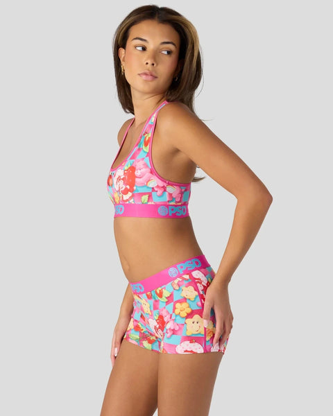 Woman wearing a pink and multicolored character-print sports bra and matching shorts with elastic waistband.