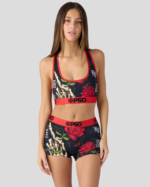 Woman wearing black sports bra and shorts with red rose print, red trim, and PSD branding.