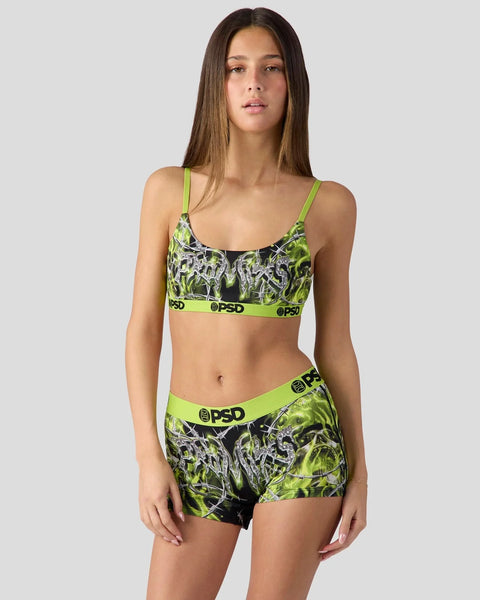 Woman wearing neon lime green and black patterned sports bra and matching shorts with PSD branding.