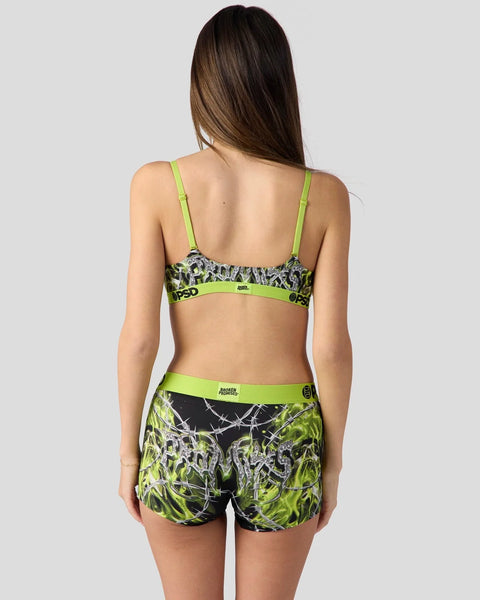Woman wearing neon green and black patterned sports bra and shorts set with thin shoulder straps, shown from behind.