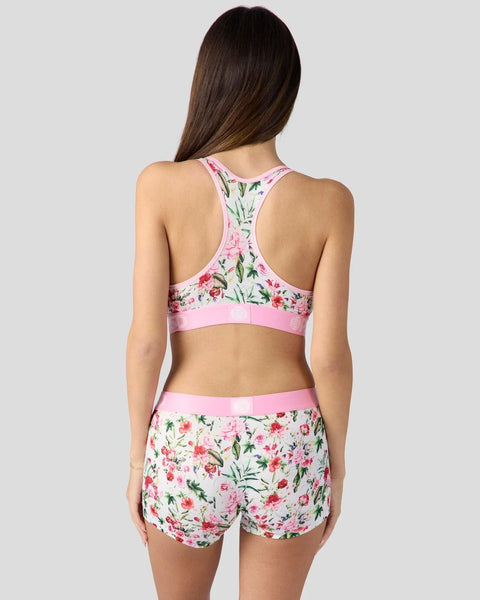Floral print sports bra and shorts set with pink trim and multicolored flowers on white background.