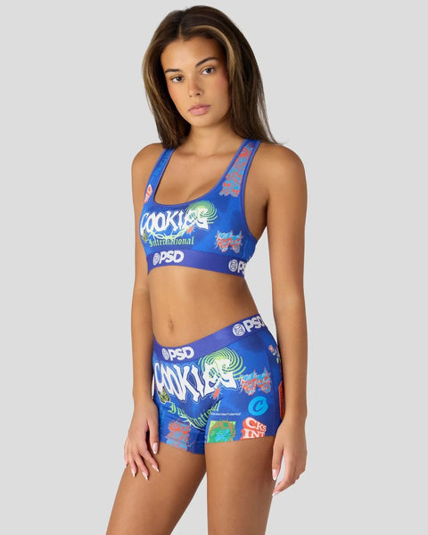 Woman wearing blue sports bra and matching shorts with colorful graphic print and brand logos.