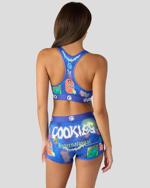 Woman wearing blue sports bra and shorts with colorful cookie brand graphics and text.