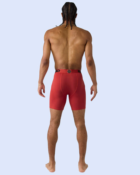 Man wearing red modal shorts with waistband detail, shown from back view against light blue background.