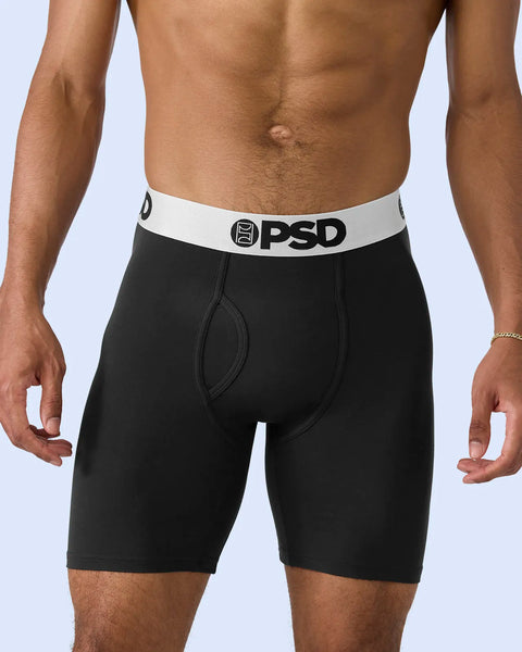 Black boxer briefs with white waistband and PSD logo on male model against light blue background.