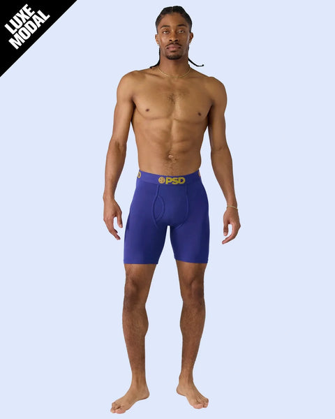 Man wearing royal blue shorts with PSD waistband and gold logo.