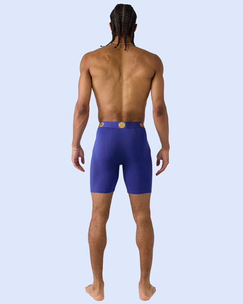 Man wearing royal blue shorts with gold belt buckle, shown from back view.