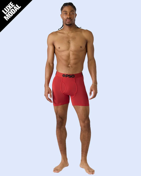 Man wearing red boxer briefs with black waistband against light blue background.
