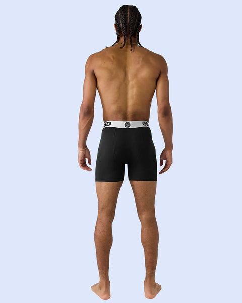 Black boxer shorts with white waistband featuring silver-toned logo detail, shown on model from behind.