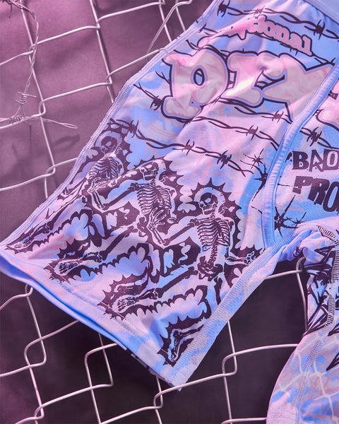 Fabric with skeleton and demon graphic design in purple and blue tones on grid patterned background.