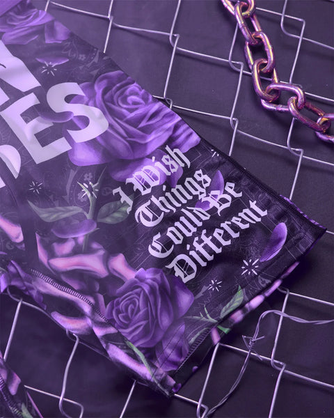 Purple pouch with rose print and text design, attached to a metallic chain strap on grid patterned background.