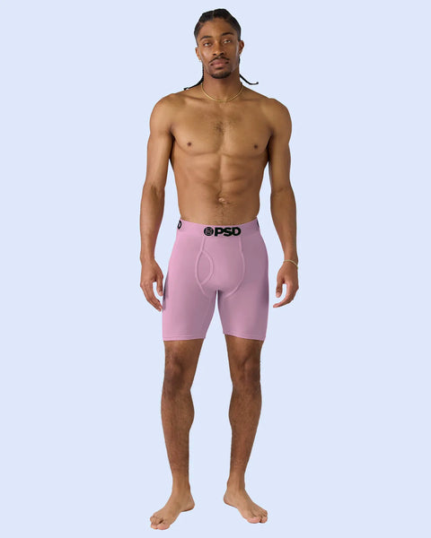 Man wearing pink modal boxer briefs with PSD waistband against light blue background.