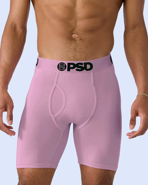 Man wearing pink modal boxer briefs with black PSD waistband against light blue background.