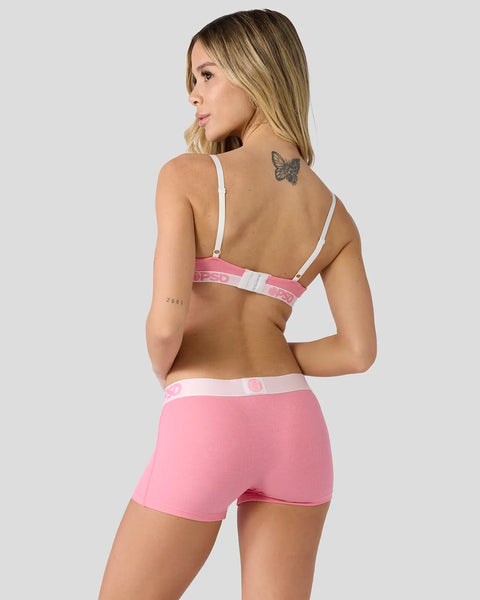 Baby pink ribbed bra and shorts set with white trim and adjustable straps, shown on model from back.