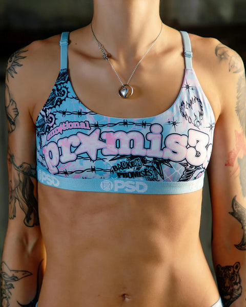 Blue and pink sports bra with graphic text print, barbed wire design, and light blue elastic band.