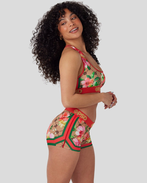 Woman wearing a red, pink, and green floral print two-piece swimsuit with matching trim details.