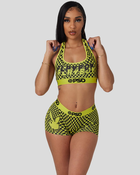 Woman wearing neon yellow and black checkered Playboy sports bra and matching shorts with PSD branding.