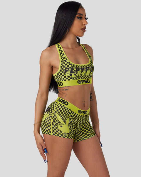 Woman wearing neon yellow and black checkered sports bra and shorts set with Playboy bunny logo and PSD branding.
