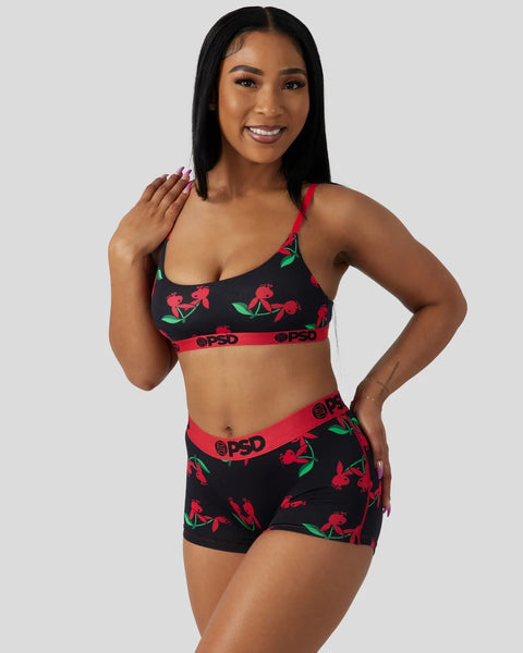 Black bra and shorts set with red cherry and green leaf print, red elastic waistband with branding.