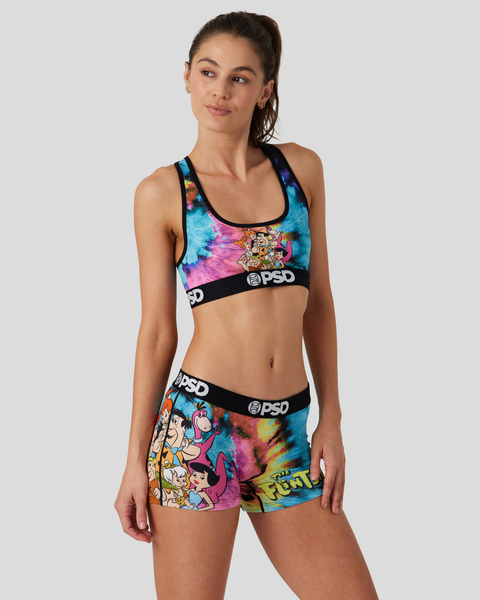Woman wearing tie-dye sports bra and shorts set with Flintstones cartoon characters and PSD branding.