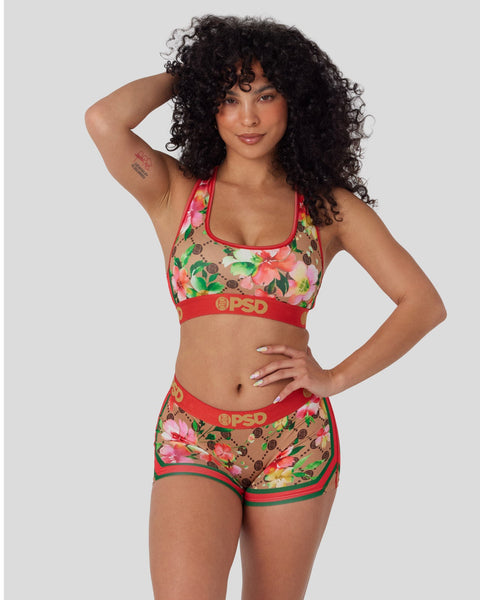 Women's sports bra and shorts set with pink floral and monogram print on tan base with red trim.