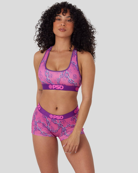 Woman wearing pink and purple PSD sports bra and matching shorts with abstract line pattern design.