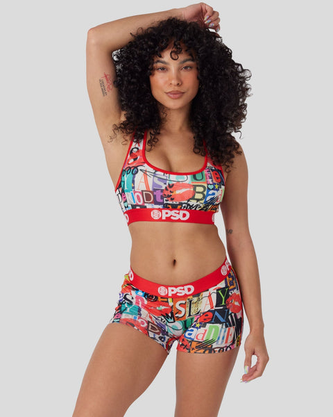 Woman wearing colorful graphic sports bra and shorts set with red trim and PSD branding.