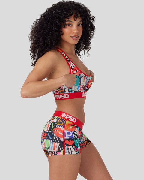 Woman wearing red sports bra and shorts with colorful geometric and text print pattern.