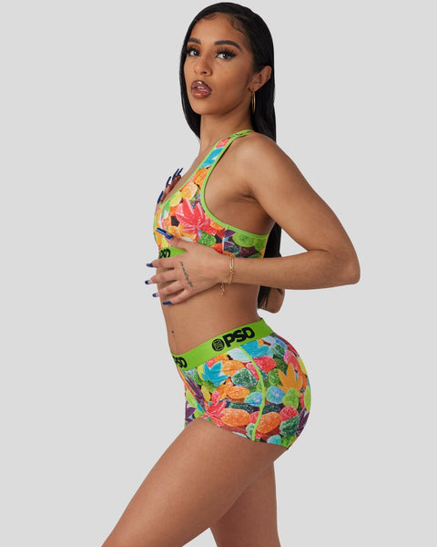 Woman wearing colorful fruit-patterned sports bra and matching briefs with green trim and PSD waistband.