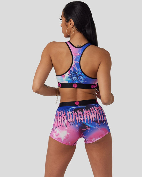 Woman wearing pink and blue tie-dye sports bra and matching shorts with metal band graphics and lightning bolt design.