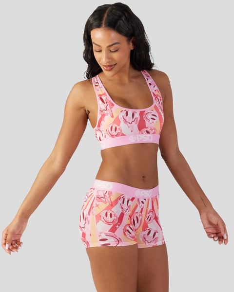 Pink sports bra and shorts set with smiley face and abstract print pattern.
