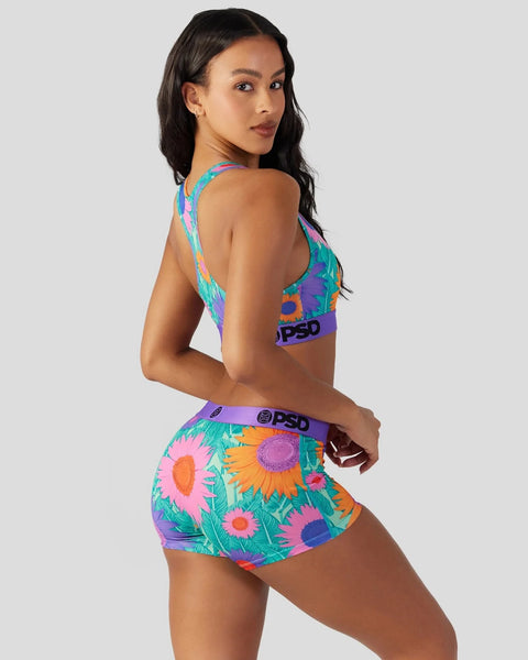 Colorful sports bra and boy shorts set with multicolor sunflower and leaf print on turquoise background.