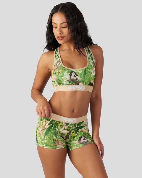 Woman wearing green floral sports bra and matching shorts with beige elastic bands.