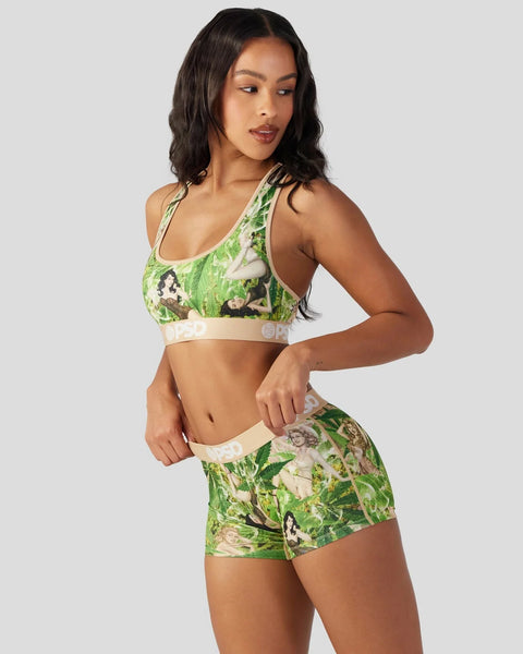 Woman wearing green floral sports bra and matching shorts with cream-colored trim and logo bands.