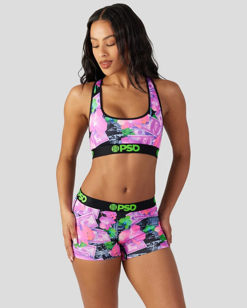 Woman wearing pink, green, and black floral sports bra and shorts set with PSD branding.