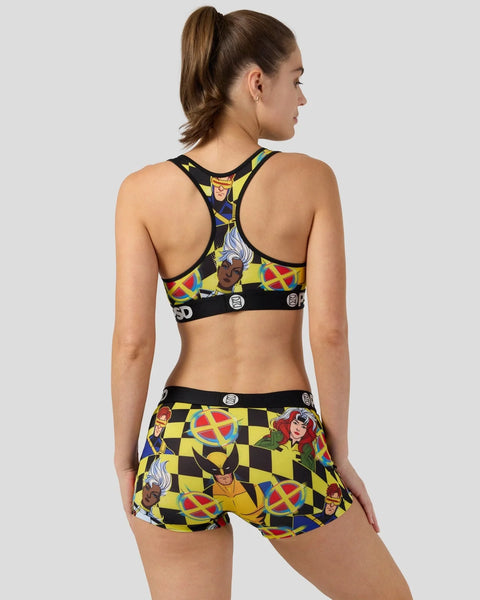 Woman wearing X-Men checkers print sports bra and shorts with character graphics and yellow-black checkered pattern.