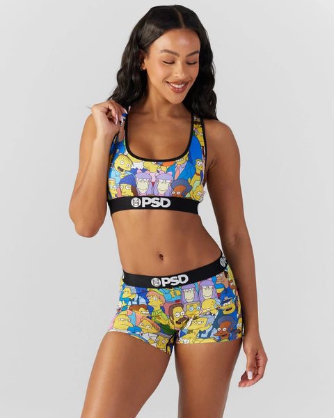 Woman wearing a blue and yellow Simpsons-print sports bra and matching shorts with black PSD waistbands.