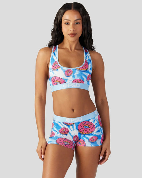 Women's sports bra and shorts set with pink donuts and blue tie-dye pattern on white background.