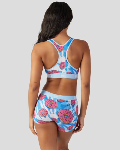 Women's sports bra and shorts set with pink donut print on blue tie-dye background, racer-back design.